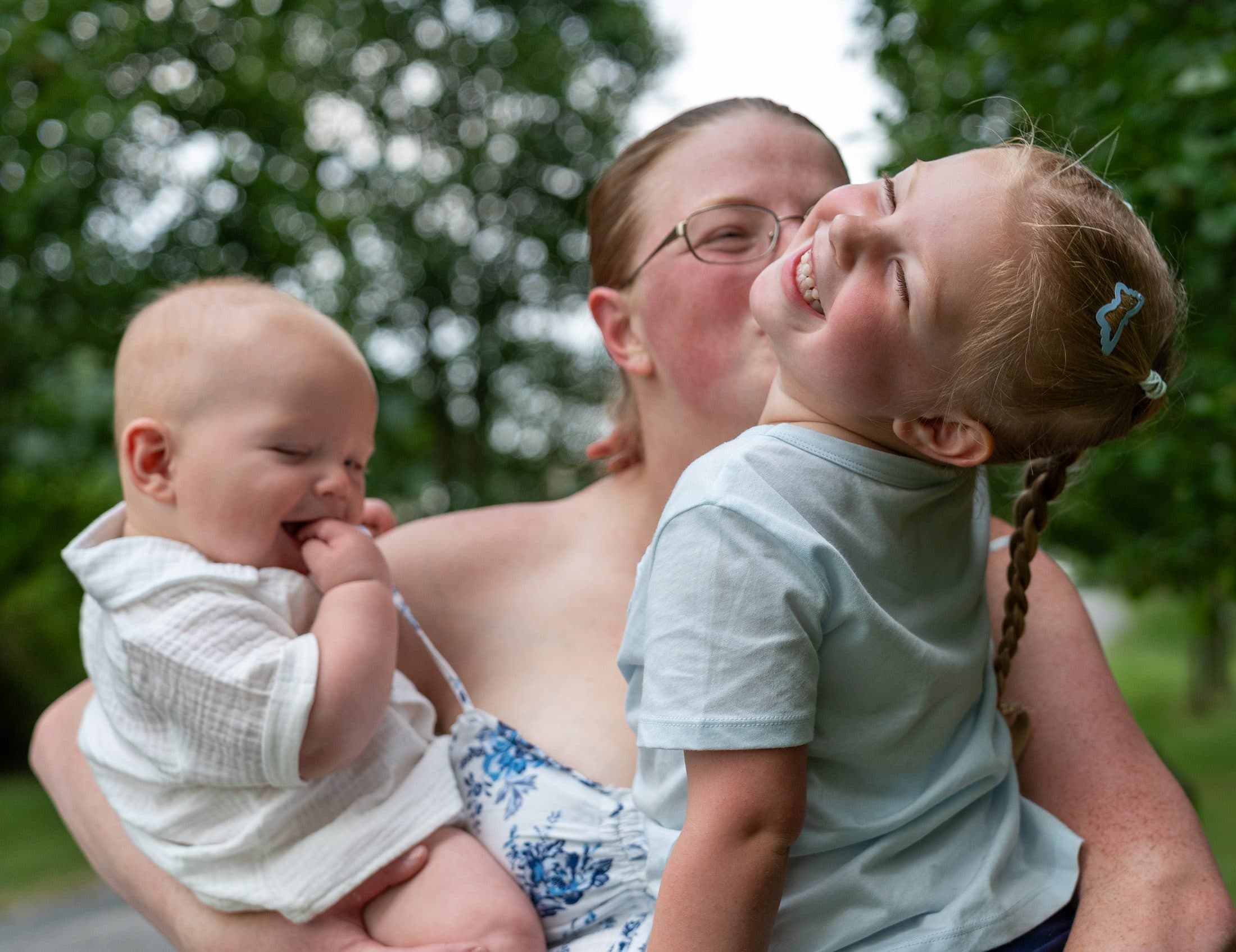 A mother laughing with her two children in her arms
