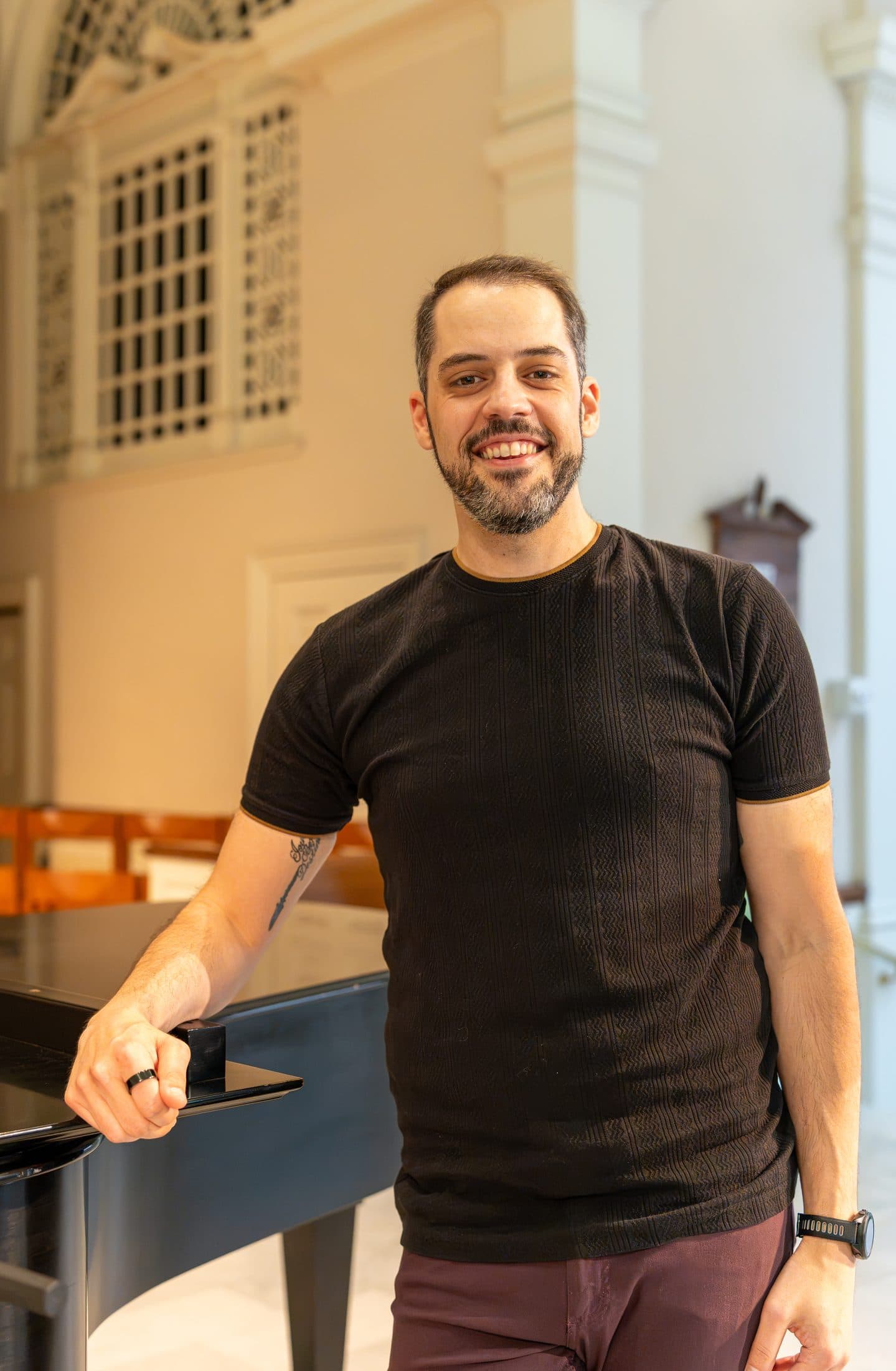 Editorial portrait of a performer beside a grand piano